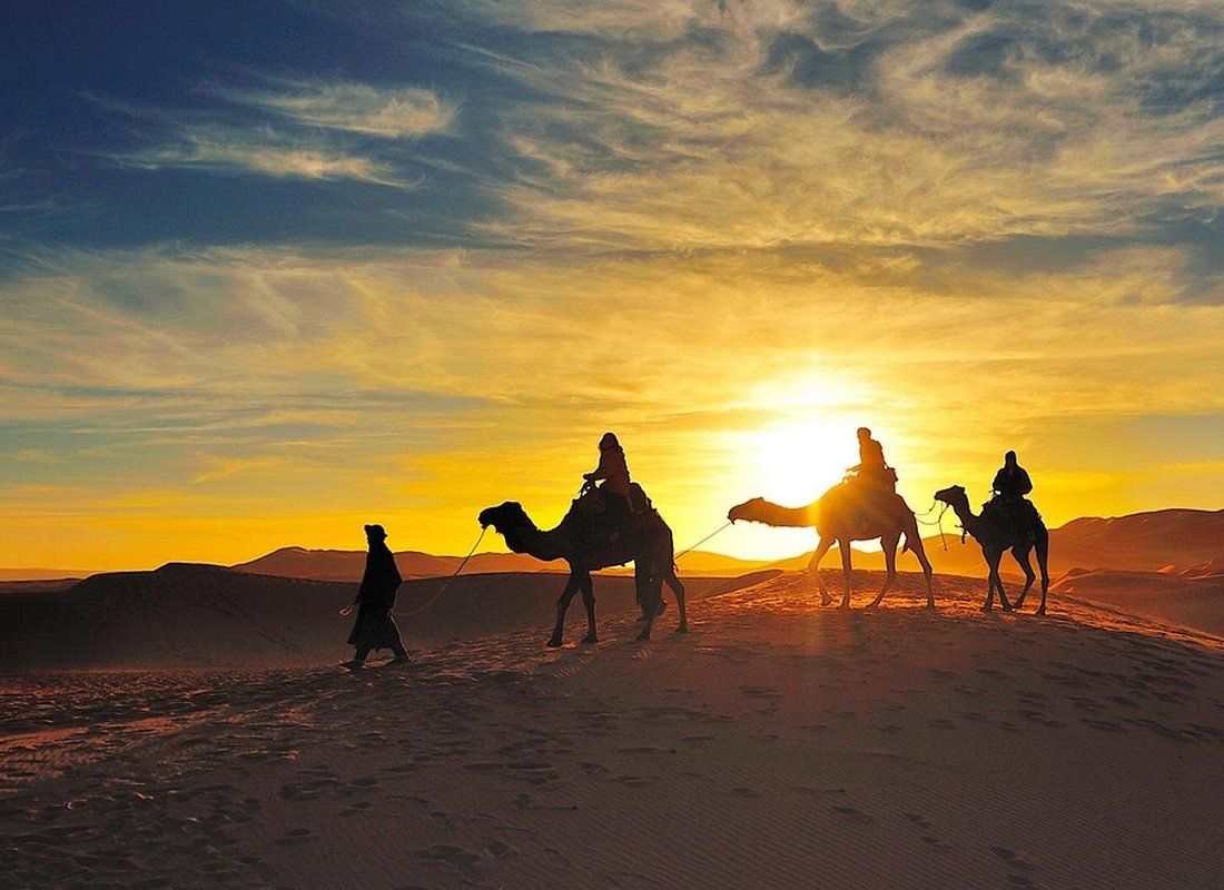 Balade à dos de dromadaire dans les dunes au coucher du soleil